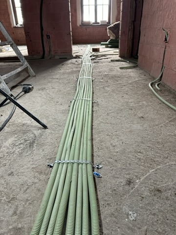 Pose de gaines et câblage électrique au sol avant chape sur un chantier CharlElec en Belgique