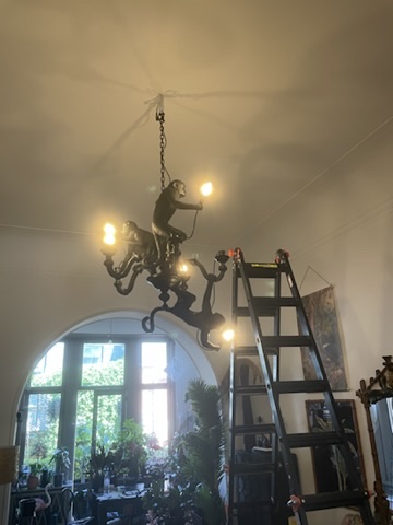 Électricien installant et raccordant un lustre décoratif en hauteur sur un chantier CharlElec en Belgique